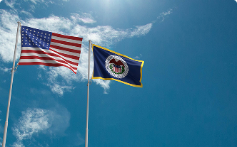Two flags waving in the wind with a clear blue sky above