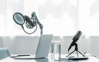 A desk with a laptop and two microphones conveying a podcast setup